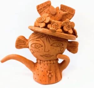 clay sculpture of girl wearing a hat with flowers & 2 birds on it